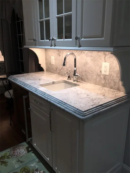 A well-lit kitchen corner with marble countertops and white cabinetry.