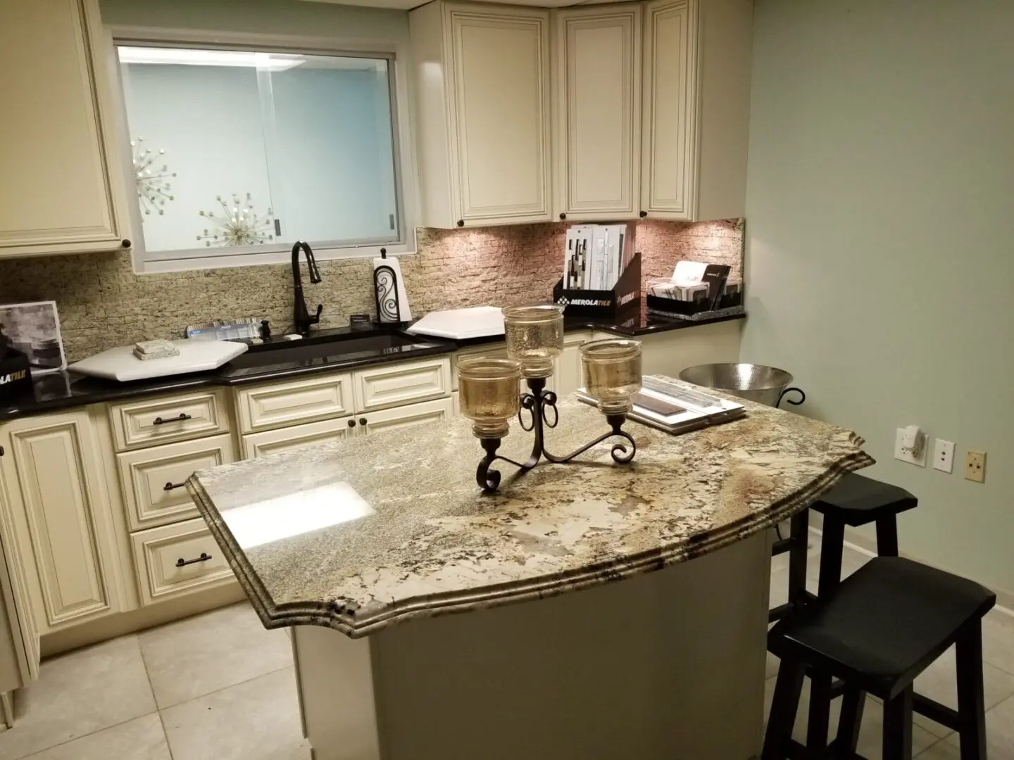 Modern kitchen interior with granite countertops and cream-colored cabinets.