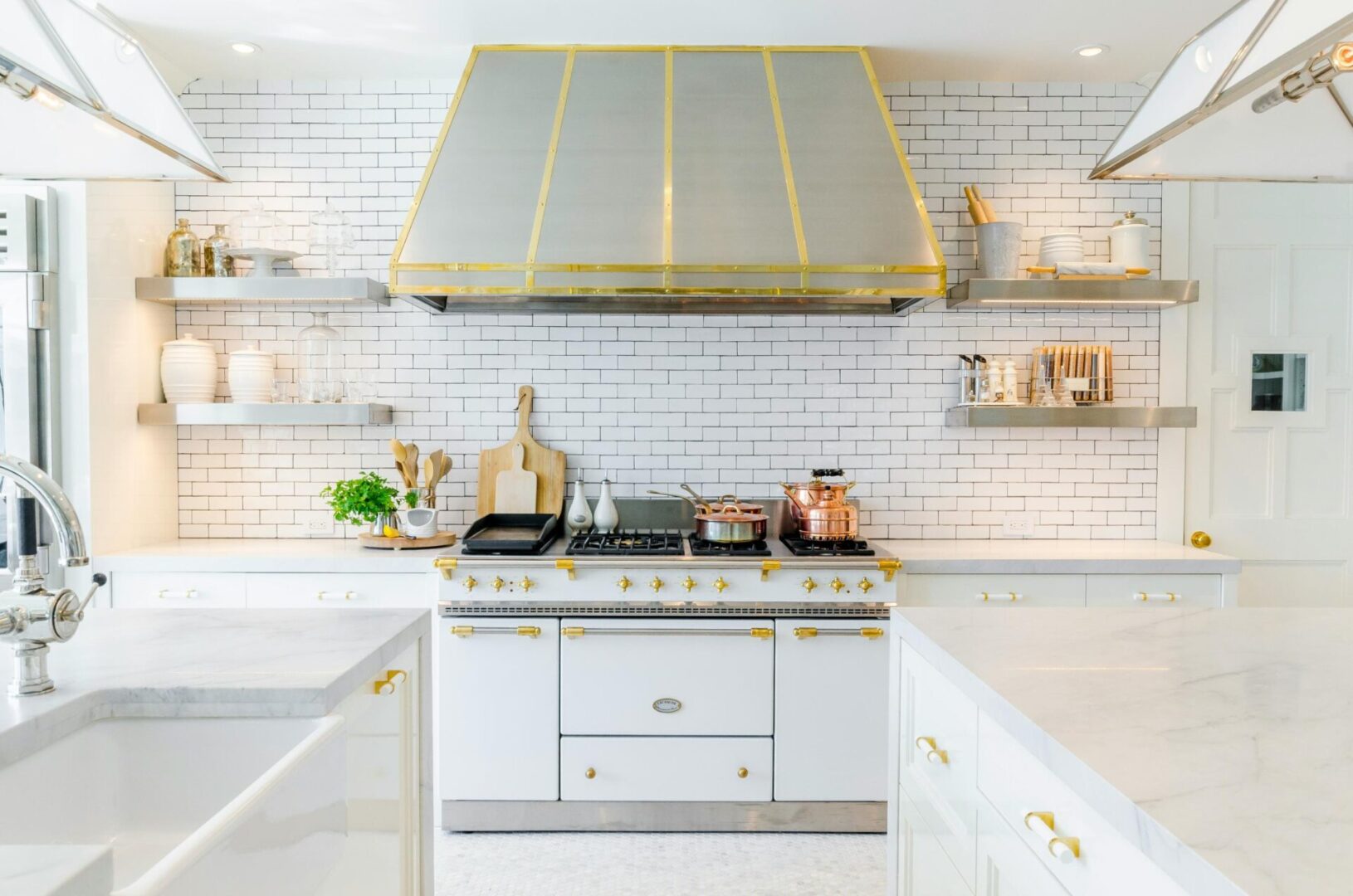 Modern kitchen with white cabinetry, marble countertops, and gold accents.