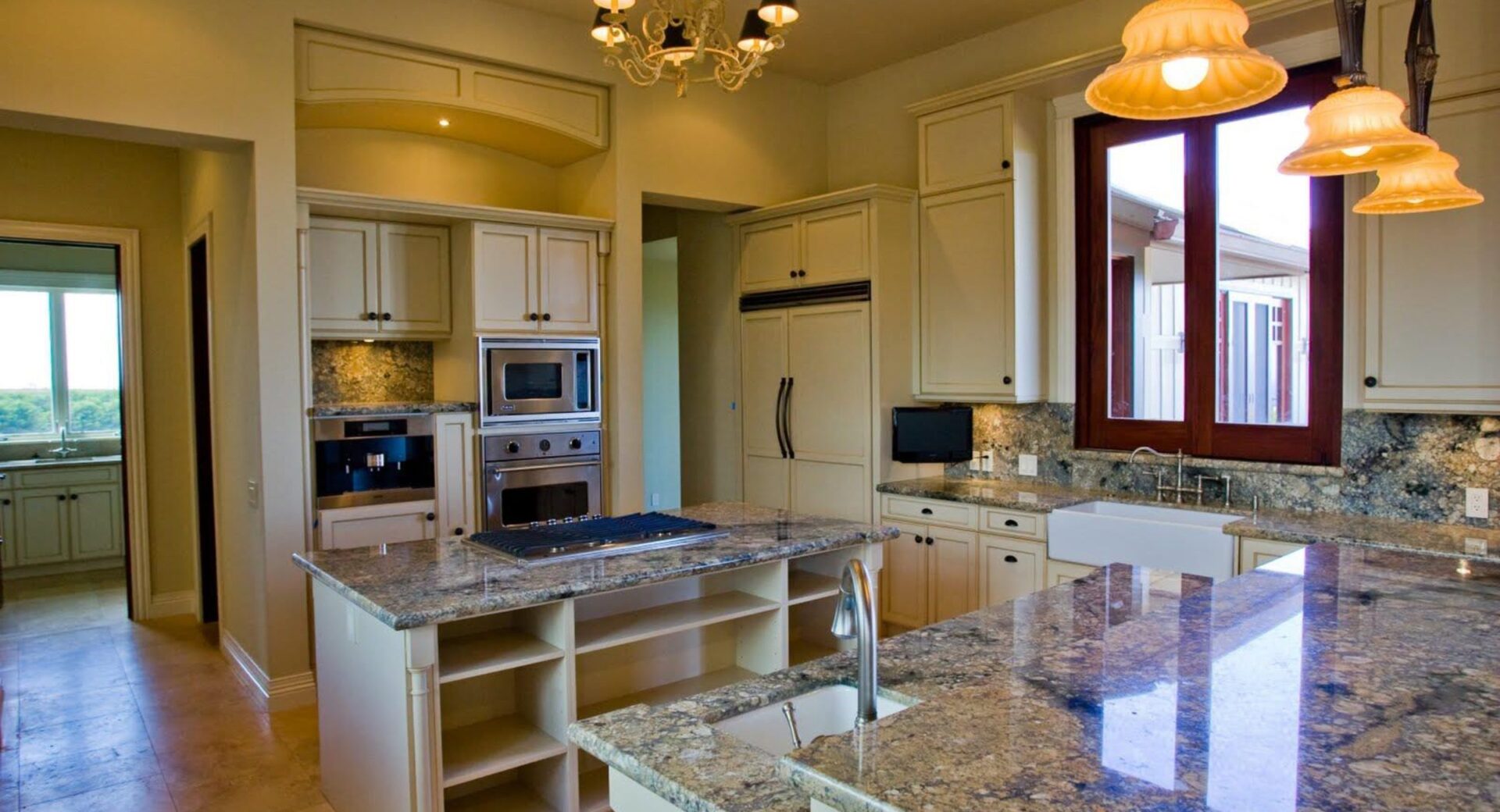 A spacious kitchen with modern appliances, granite countertops, and pendant lighting.