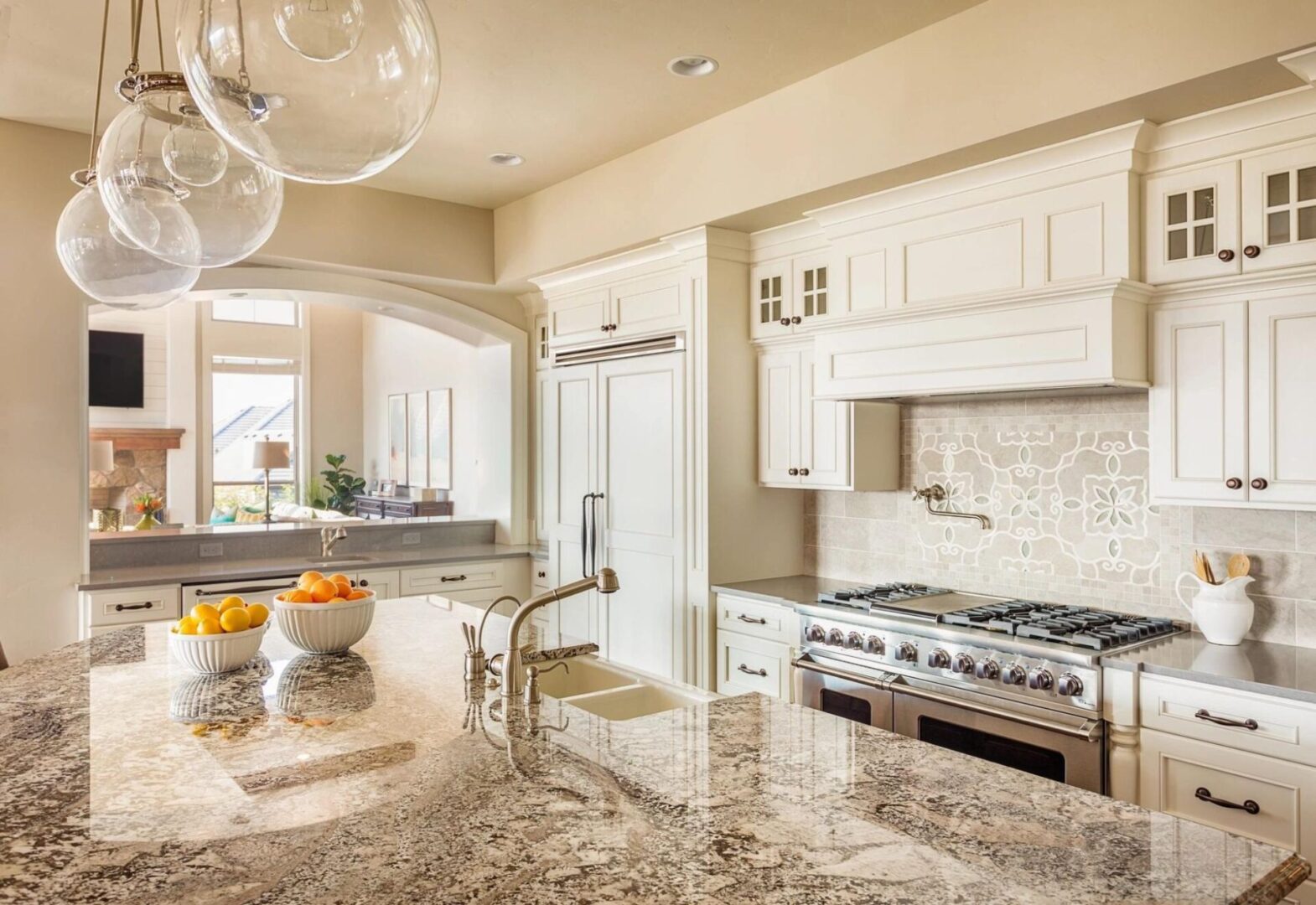 A bright, modern kitchen with white cabinetry, stainless steel appliances, and a marble countertop.